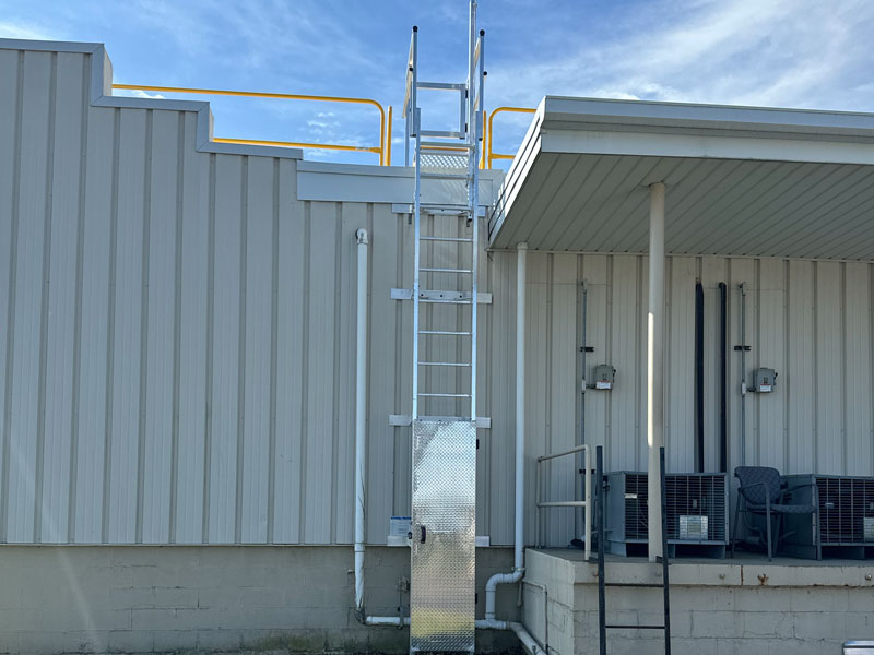 Modular aluminum ladder with crossover platform, elongated wall brackets, fall arrest system, safety gate, and lockable access door
